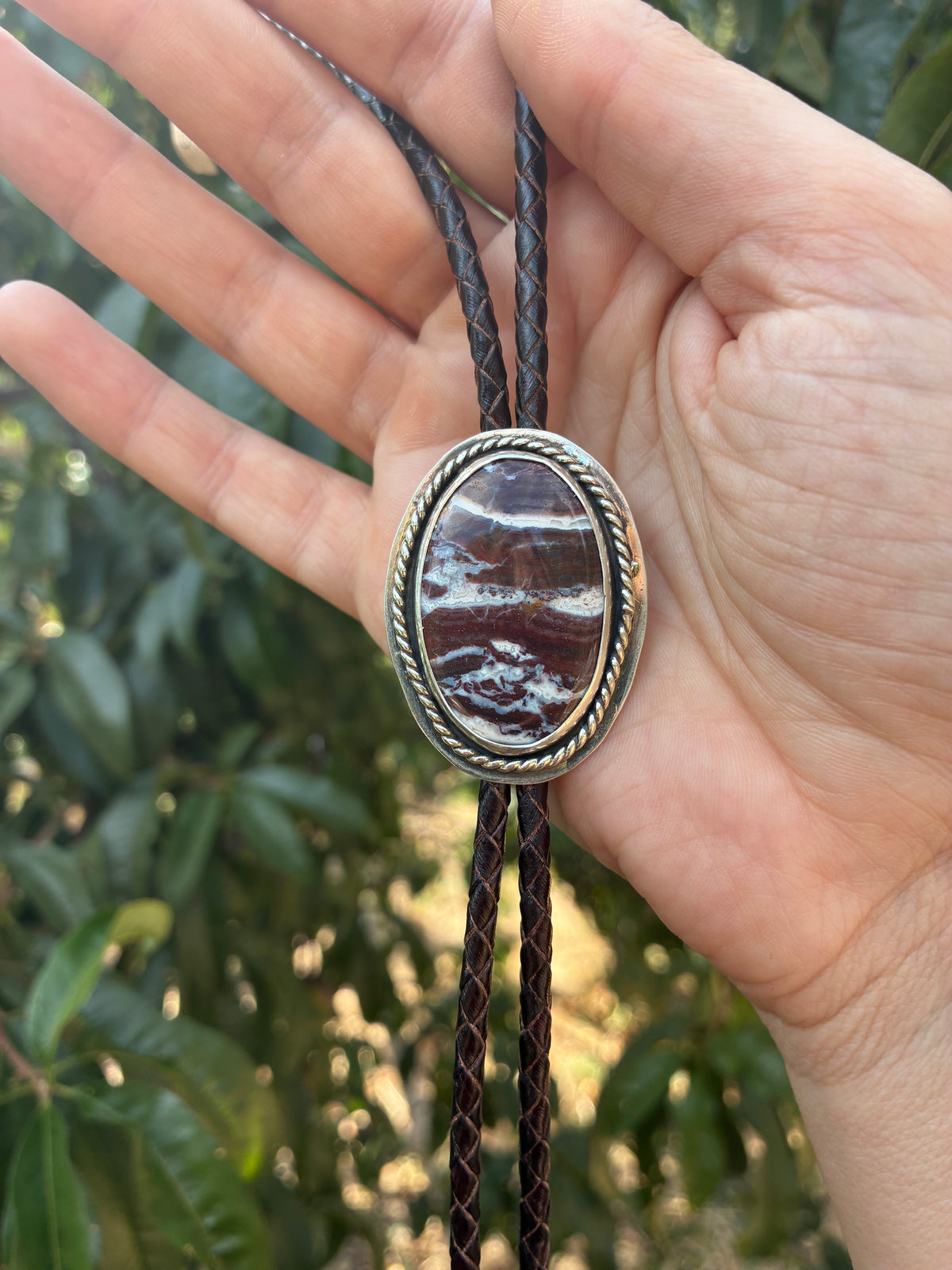 Handmade Red Creek Jasper bolo tie held in hand
